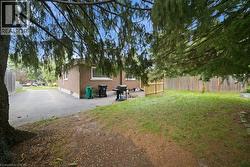 Expansive yard space featuring a mature tree, privacy fencing, and a paved driveway - 