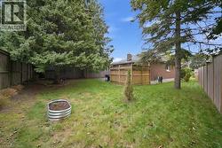 Expansive backyard featuring a manicured lawn, established trees, and a raised garden bed - 