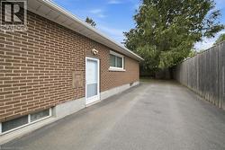 Brick exterior with a white storm door, single-pane window, and paved driveway - 