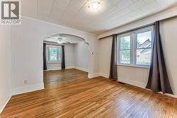Hardwood flooring throughout, featuring a cased archway and white paneled walls - 