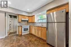 Kitchen featuring wood cabinetry, a stainless steel refrigerator, white range, and a double basin sink - 