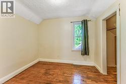 Room featuring wood-finish flooring, light-toned walls, and a window with natural light - 