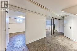 Finished basement space featuring concrete flooring, multiple doorways, and exposed ceiling beams - 