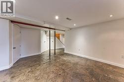 Expansive finished basement space featuring recessed lighting, a concrete-style floor, and multiple storage doors - 