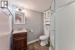 Bathroom featuring a dark wood-finish vanity with an integrated sink, wall-mounted mirror, and overhead light fixture - 