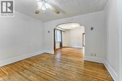 Room featuring wood-finish flooring, white walls, and a ceiling fan with light fixture - 