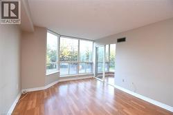 Expansive living area featuring laminate wood flooring, a curved window wall, and a sliding glass door - 