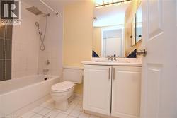 Bathroom featuring white subway tile surround with a decorative accent, a rainfall showerhead, a white vanity with a built-in sink, and a framed mirror with overhead lighting - 