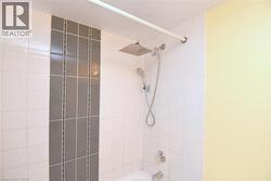 Shower enclosure with white subway tile and a vertical accent stripe of gray rectangular tiles - 