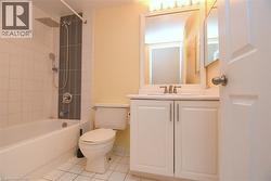 Bathtub with tiled surround and rain showerhead, white vanity with integrated sink, framed mirror, and tile flooring - 