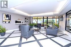 Recessed lighting within a coffered ceiling, modern wall-mounted fireplace, floor-to-ceiling windows, and white and black patterned tile flooring - 