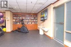 Recessed lighting, wood trim details, built-in shelving, wall-mounted television, and a glass-paneled door - 