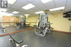 Fitness center featuring rubber flooring, mirrored wall, wood-finish barre, and multiple exercise machines - 