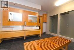 Dual vessel sinks with modern fixtures, wood-finish vanity, recessed lighting, and two glass-enclosed shower stalls - 
