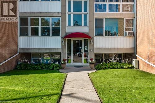 Building exterior featuring a red awning, glass entry door, and multiple windows - 824 Brant Street Unit# 9, Burlington, ON 