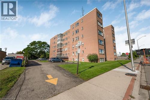 Brick exterior building with multiple windows, paved parking area, and manicured lawn - 824 Brant Street Unit# 9, Burlington, ON 