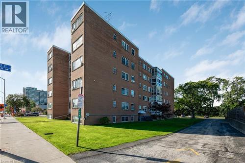 Brick exterior building with multiple windows, featuring a landscaped lawn and mature trees - 824 Brant Street Unit# 9, Burlington, ON 