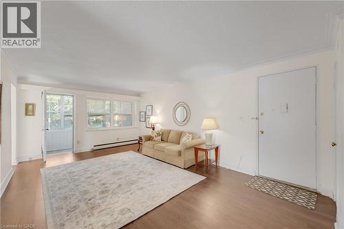 Spacious room with wood-finish flooring, white walls, multiple windows, and a partially open solid exterior door - 824 Brant Street Unit# 9, Burlington, ON 