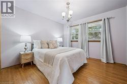 Bedroom featuring wood-type flooring and hanging lights - 