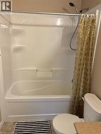 Bathtub with integrated shower surround, handheld shower head, and adjacent toilet - 