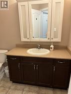 Vanity featuring an integrated sink, dark wood-finish cabinetry, and a light-toned countertop - 