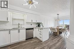 Modern kitchen featuring white cabinetry, light-toned countertops, subway tile backsplash, and stainless steel appliances - 