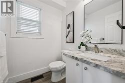 White vanity with a rectangular undermount sink, a polished chrome faucet, and a stone-finish countertop - 