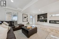 Recessed lighting illuminates this living space featuring a built-in electric fireplace and integrated shelving - 