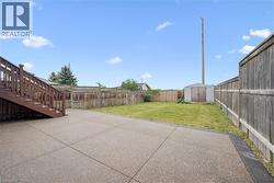 Expansive backyard featuring a concrete patio, wood fencing, and a storage shed - 