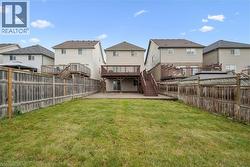 Expansive backyard featuring a manicured lawn, concrete patio, and privacy fencing - 