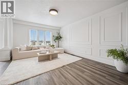 Wood-finish flooring throughout, large picture windows, decorative wall molding, and a prominent architectural column - 