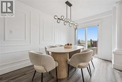 Decorative wall paneling, modern linear chandelier, sliding glass door, wood-finish flooring, and architectural column - 