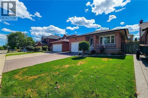 Brick exterior with an inviting front porch, attached double garage, and a paved driveway - 276 Greencedar Drive, Hamilton, ON 
