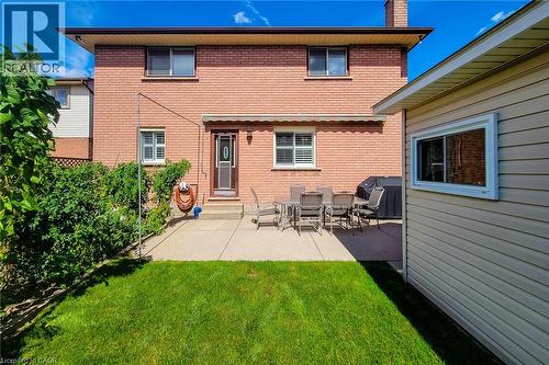 Brick exterior with a ground-level patio, mature landscaping, and a separate structure with horizontal siding - 276 Greencedar Drive, Hamilton, ON 