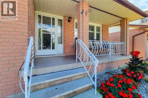 Brick exterior featuring a covered porch, decorative white railings, and a tiled entryway - 276 Greencedar Drive, Hamilton, ON 