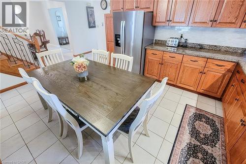 Kitchen featuring wood cabinetry, solid surface countertops, tile flooring, and a stainless steel refrigerator - 276 Greencedar Drive, Hamilton, ON 