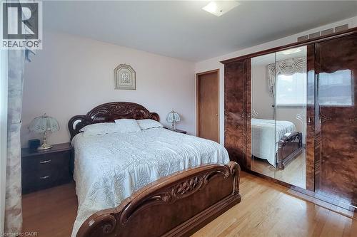 Light wood-finish flooring with a wood door and custom built-in wardrobe featuring mirrored panels - 276 Greencedar Drive, Hamilton, ON 