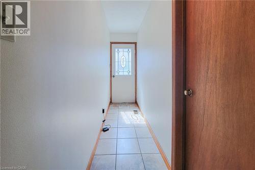 Entryway featuring ceramic tile flooring, a paneled door with decorative glass, and wood trim - 276 Greencedar Drive, Hamilton, ON 
