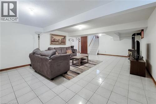 Spacious room featuring white tile flooring, white walls, exposed ceiling beams, a wood-finish door, and a staircase with white risers - 276 Greencedar Drive, Hamilton, ON 