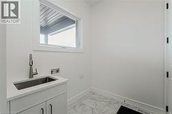 Utility sink with a gooseneck faucet, white cabinetry, and a light-toned countertop - 