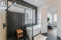 Walk-in shower with a matte black fixture, black tiled walls, and a glass enclosure - 