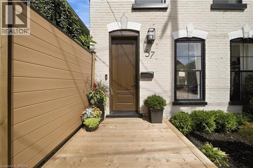 White brick exterior with black framed windows, a solid wood entry door, and wood plank decking - 57 Terrace Hill Street, Brantford, ON 