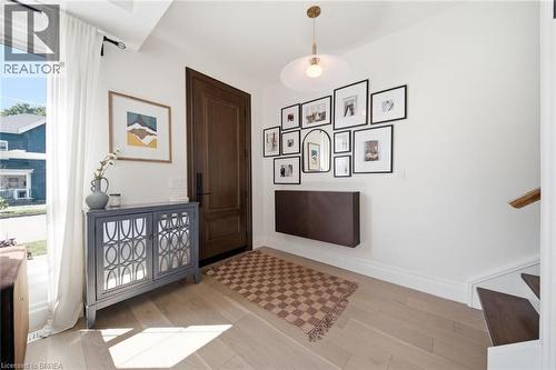 Light wood-finish flooring, a contemporary pendant light fixture, and a solid wood front door - 57 Terrace Hill Street, Brantford, ON 