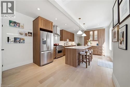 Gourmet kitchen with wood-finish cabinetry, stainless steel appliances, a central island with countertop seating, recessed lighting, and light wood-finish flooring - 57 Terrace Hill Street, Brantford, ON 