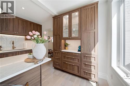 Custom wood-finish cabinetry with glass-front display, quartz countertops, and light wood-finish flooring - 57 Terrace Hill Street, Brantford, ON 
