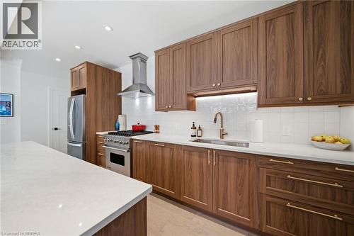 Wood-finish cabinetry with gold-tone hardware, stainless steel appliances, white countertops, tile backsplash, and recessed lighting - 57 Terrace Hill Street, Brantford, ON 