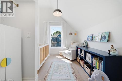 Angled ceiling room with a single window, a contemporary pendant light fixture, and light-toned wood-finish flooring - 57 Terrace Hill Street, Brantford, ON 