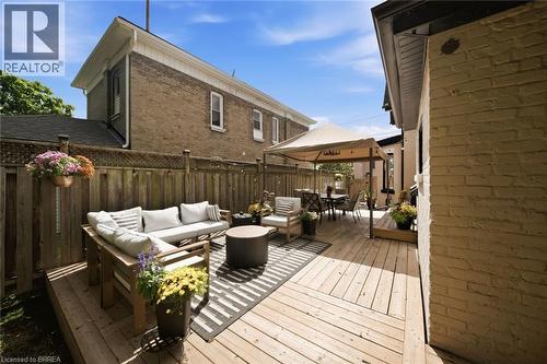 Expansive wooden deck with a privacy fence, featuring a dining area with a canopy and additional seating - 57 Terrace Hill Street, Brantford, ON 