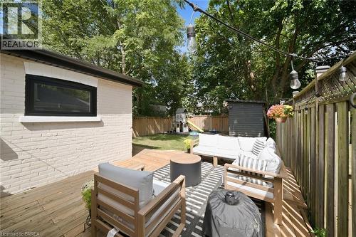 Expansive wood deck with a privacy fence, string lighting, and a brick exterior - 57 Terrace Hill Street, Brantford, ON 