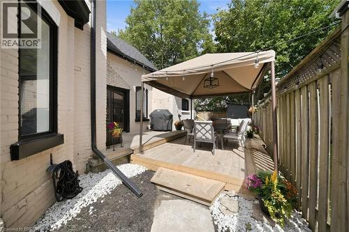 Wood deck with a canopy, privacy fencing, exterior brickwork, and dark-framed windows - 57 Terrace Hill Street, Brantford, ON 